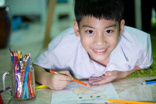 Asian child in student uniform painting on a white paper