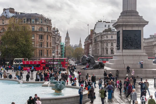 Tourists visit Trafalgar Square in London on a cloudy day