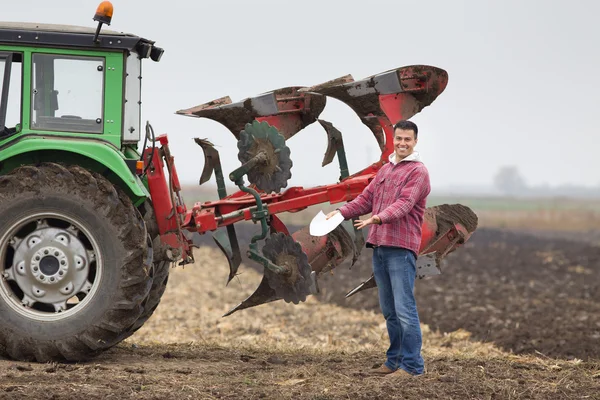 Happy farmer beside plough