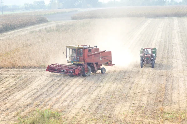 Combine and tractor in soybean field