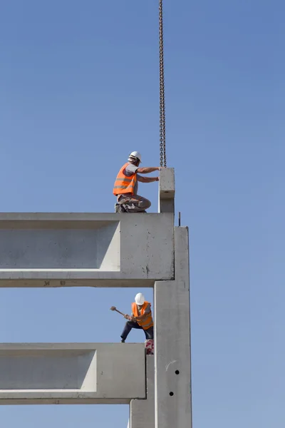 Height worker placing truss on building skeleton