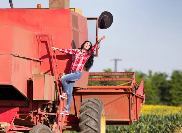 Woman throwing hat from combine harvester