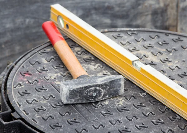 Hammer and level on manhole cover