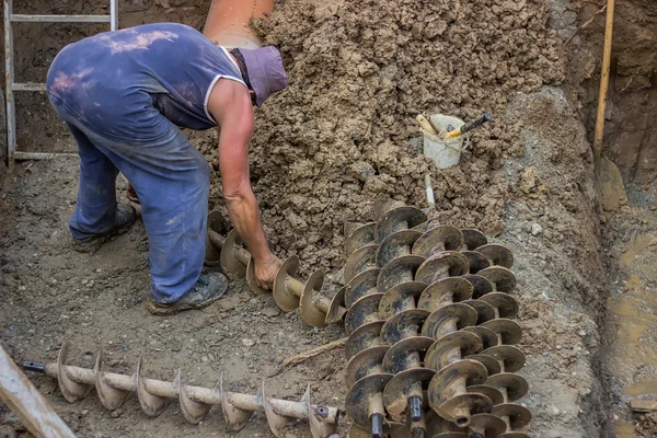 Worker packing drill drilling augers after dirt drill