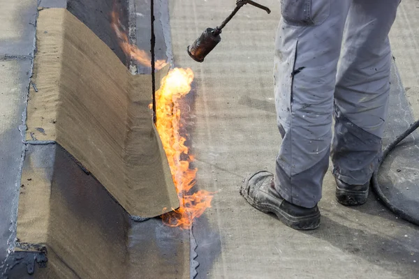 Worker heating and melting bitumen felt