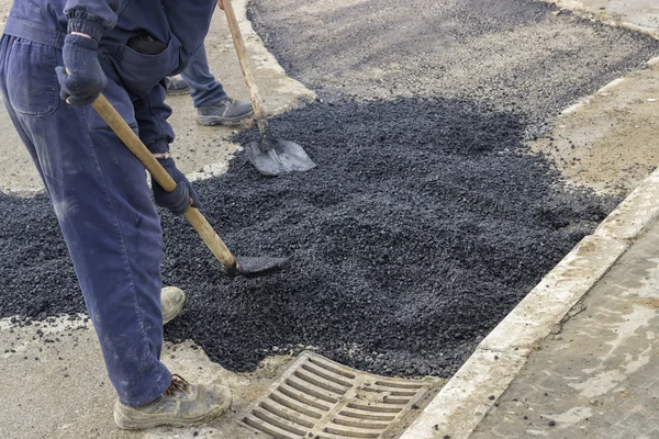 Asphalt workers with shovels patching asphalt 2