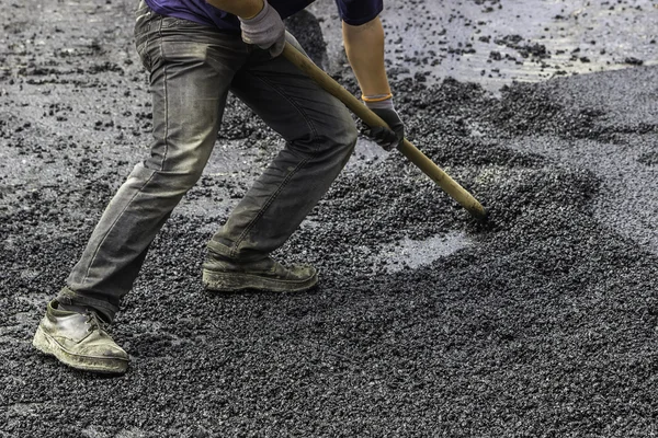 Pavement worker spread asphalt with shovel 2