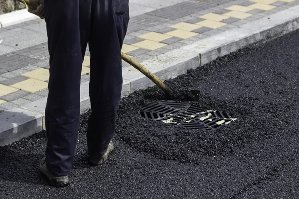 Worker using asphalt lute to level the asphalt 2