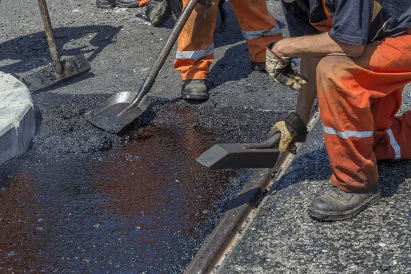 Workers using a asphalt tool to spread mastic asphalt