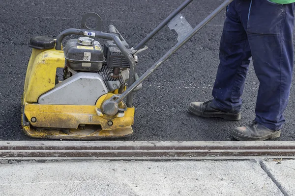 Road repairing with vibrating compactor plate