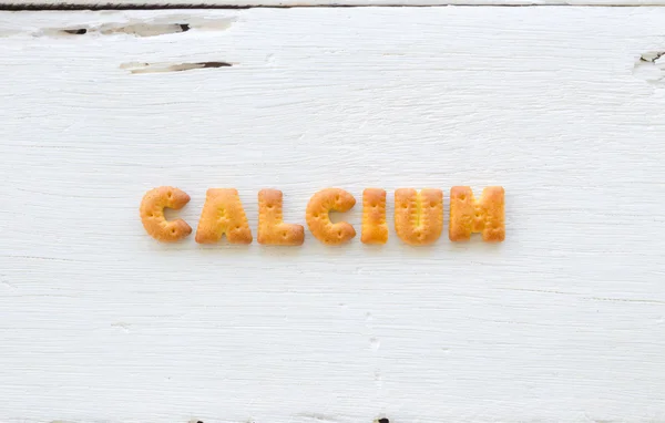 Word CALCIUM Alphabet crackers on wood background