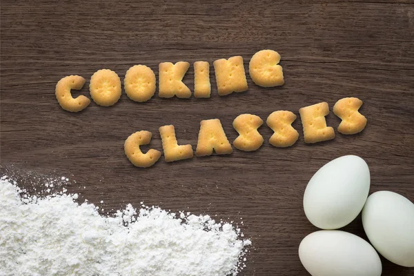 Letter biscuits word COOKING CLASSES on kitchen table background