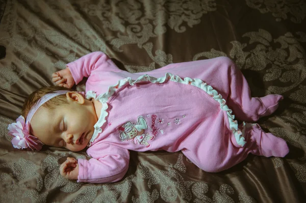 Image of cute little girl in pink suit indoor. Newborn baby