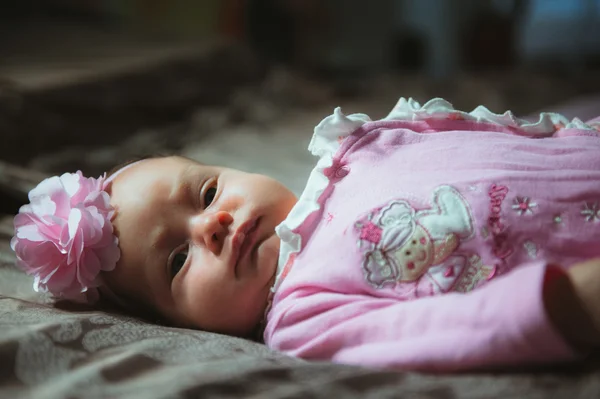 Image of cute little girl in pink suit indoor. Newborn baby