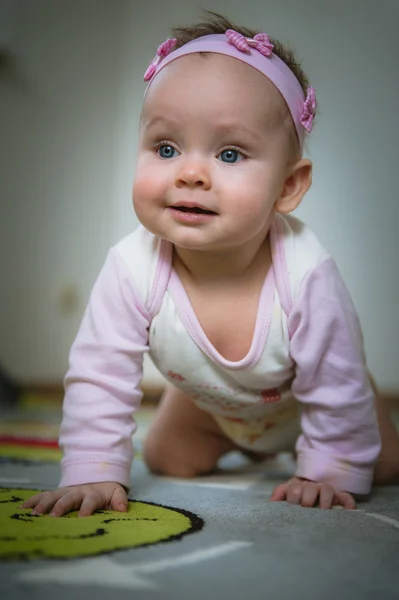 Adorable baby girl crawls on all fours floor at home. Smiling