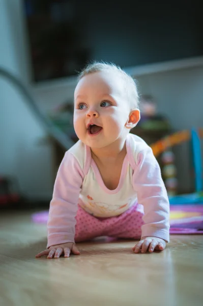 Adorable baby girl crawls on all fours floor at home