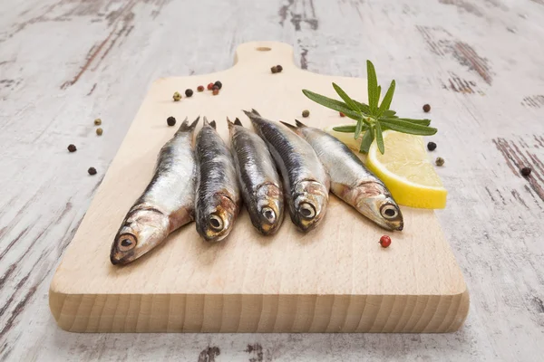 Sardnines on wooden kitchen board.