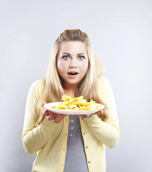 Young girl with potato chips. She thinks. Blonde watch your diet