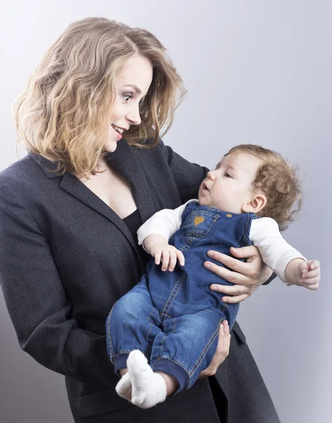 Beautiful blonde with her little son on hands. Happy business woman. Family life. Children. Young mother