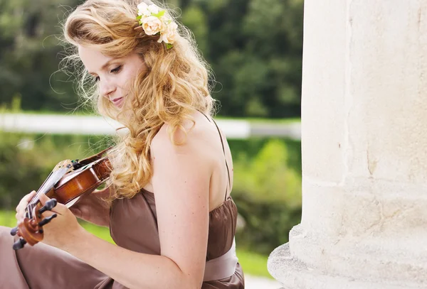 Beautiful smiling girl playing on the violin outdoors. Musician for the wedding.Violin under the open sky