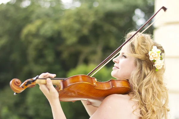 Beautiful smiling girl playing on the violin outdoors. Musician for the wedding.Violin under the open sky