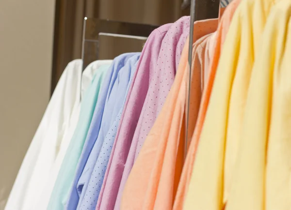 Bright colored shirts on hangers. Cotton shirts at the supermarket. Qualitative clothes