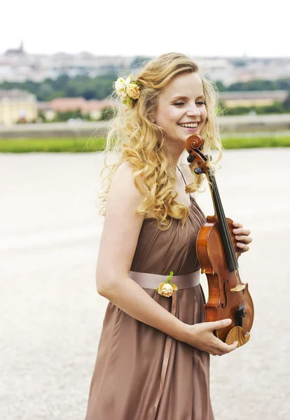 Beautiful smiling girl with a violin outdoor.Beautiful smiling girl playing on the violin outdoors. Musician for the wedding.Violin under the open sky