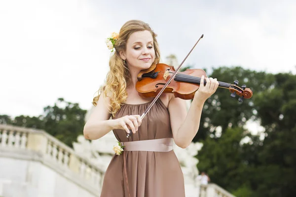 Beautiful smiling girl playing on the violin outdoors. Musician for the wedding.Violin under the open sky