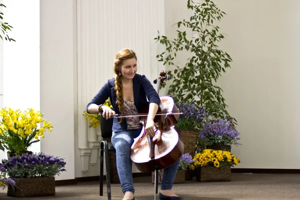 Young girl playing the cello in a large bright hall .Portrates beautiful girl with long hair. Musical Instruments