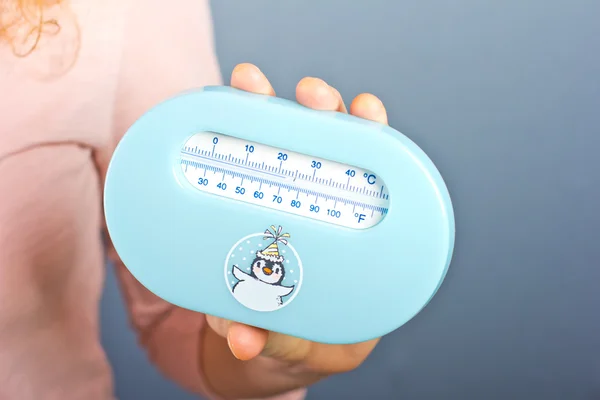 Young pregnant woman measures the temperature in the room. Children's room thermometer