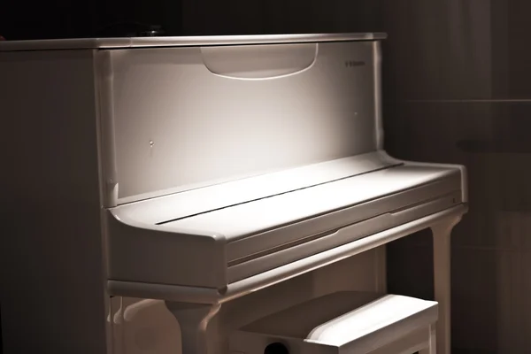 White piano in the dark. Piano chair