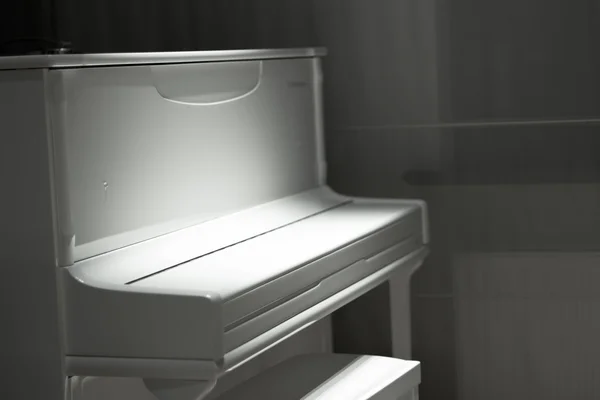 White piano in the dark. Piano chair