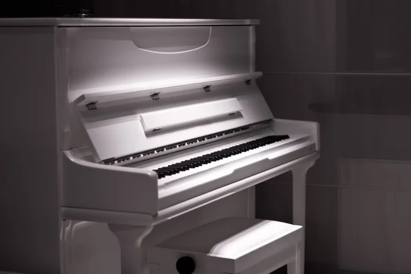 White piano in the dark. Piano chair