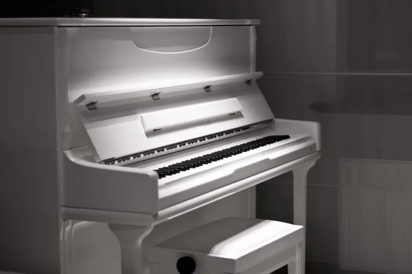 White piano in the dark. Piano chair