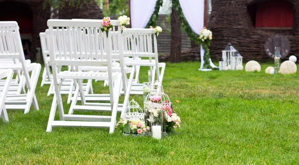 Destination wedding ceremony. Wedding white chairs on green grass