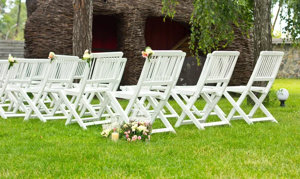Destination wedding ceremony. Wedding white chairs on green grass