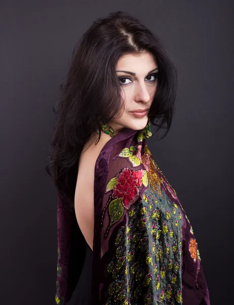 Attractive brunette in a bright attire on a black background. Fashion portrait. Portrait of a beautiful brunette. Bright embroidered handkerchief