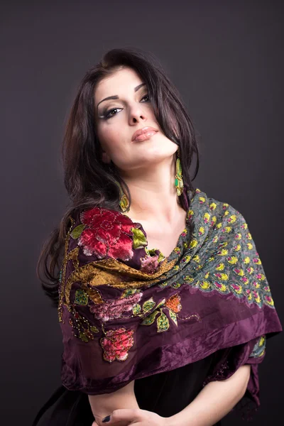 Attractive brunette in a bright attire on a black background. Fashion portrait. Portrait of a beautiful brunette. Bright embroidered handkerchief