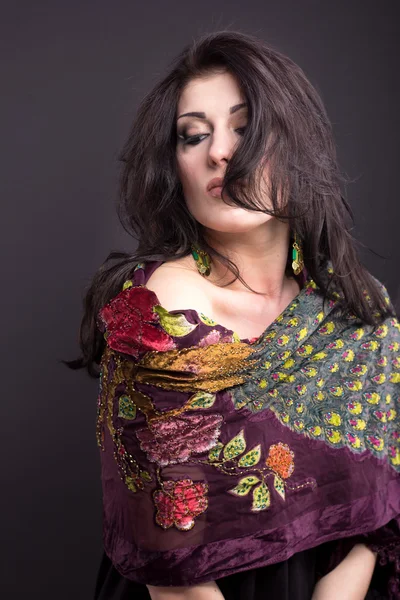 Attractive brunette in a bright attire on a black background. Fashion portrait. Portrait of a beautiful brunette. Bright embroidered handkerchief