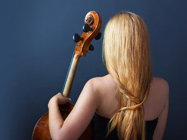 Beautiful girl with a cello on a black background. Cellist. Girl musician.