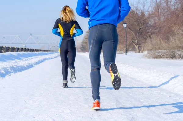 Runners. Legs, back view. Young running couples. Sport man & woman jogging on winter park