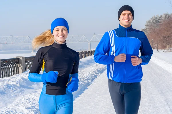 Runners. Young runniRunners. Young running couples. Sport man & woman jogging on winter embankmentng couples. Sport man & woman jogging on win