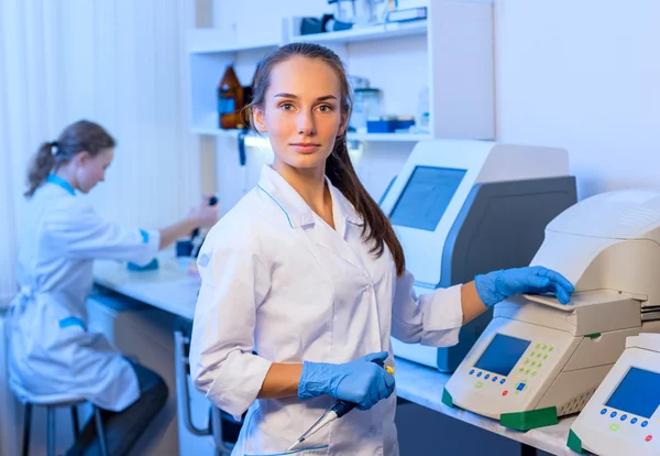 Woman researcher chemist in a white lab bathrobe working with equipment in the modern laboratory