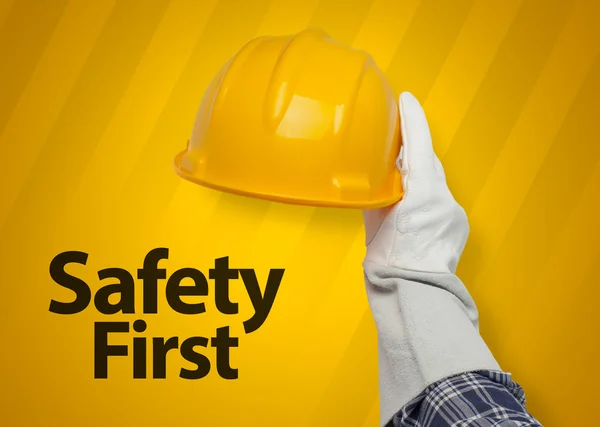 Hand holding yellow hardhat. safety first concept.
