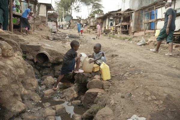 Boys take a water for drinking on a street of Kibera, Nairobi, Kenya.