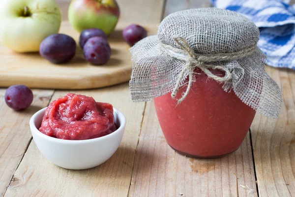 Homemade preserved apple and plum puree on wooden rustic table