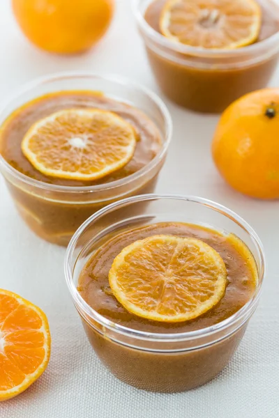 Mandarin jam in glass jars with mandarin slices on white table