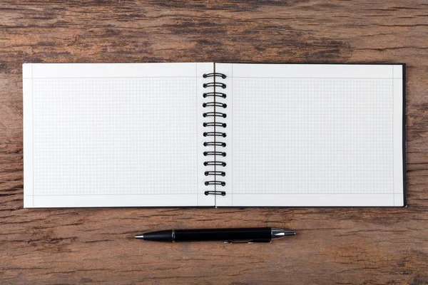 Blank note pad with pen on wood background