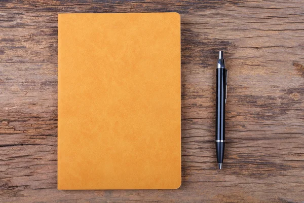 Blank note pad with pen on wood background