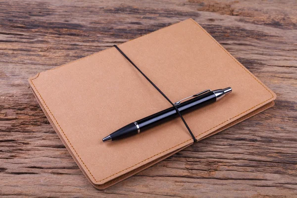 Blank note pad with pen on wood background